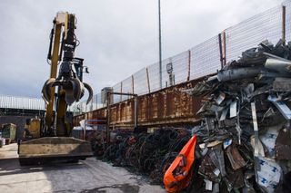 A claw crane operates beside assorted scrap metal at a metals recycling yard in Paris, France