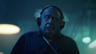 Danny DeVito as a ghoulish janitor wearing headphones in Beetlejuice Beetlejuice