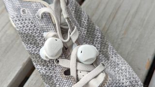 The Adidas FWD-02 wireless earbuds resting on a pair of Adidas running shoes