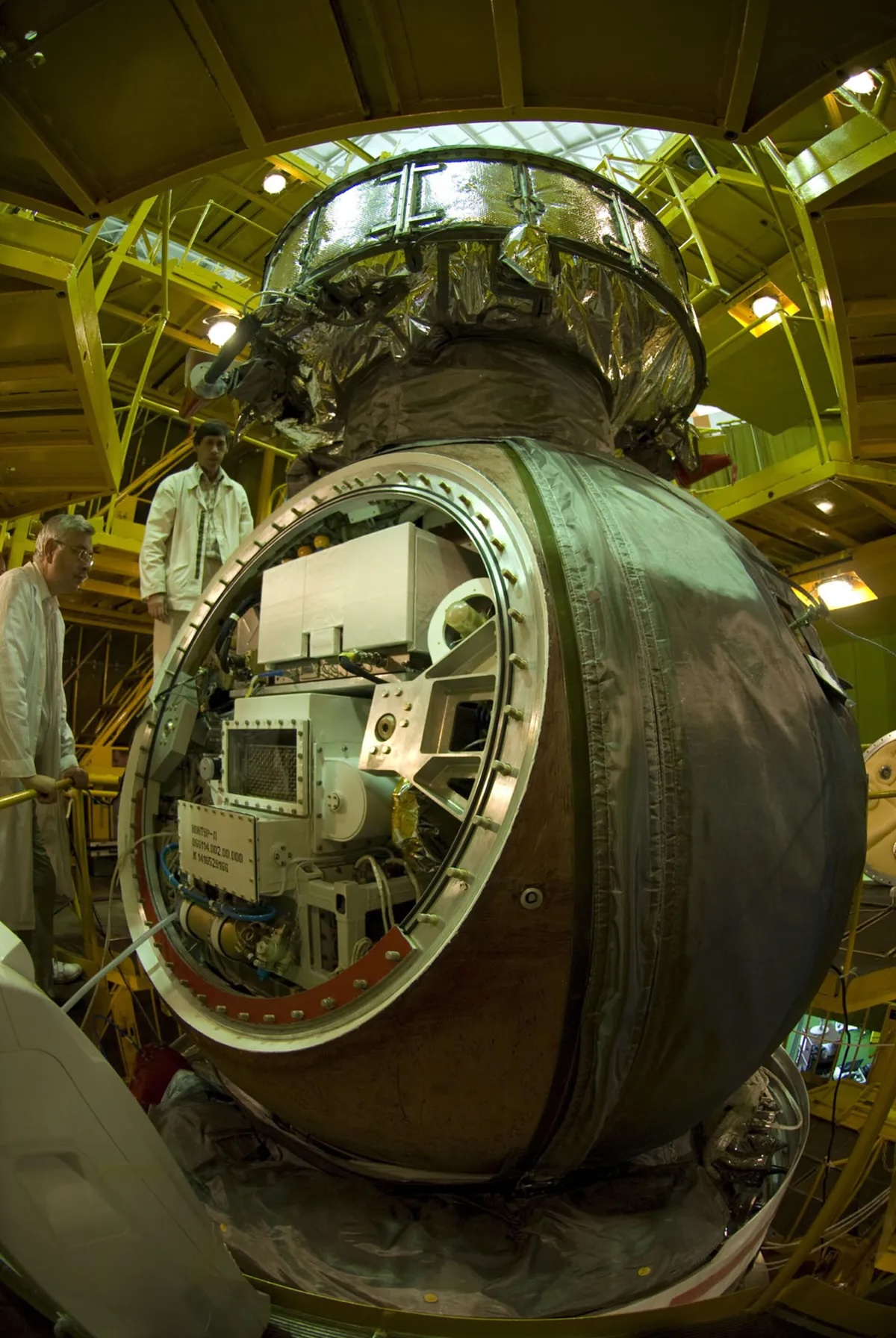 a dark, spherical space capsule is open on one end, showing different boxes and racks for different experiments.