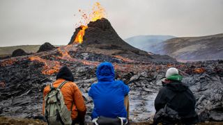 Hikers look at the lava flowing from the erupting Fagradalsfjall volcano near Reykjavik, Iceland, on March 21, 2021.