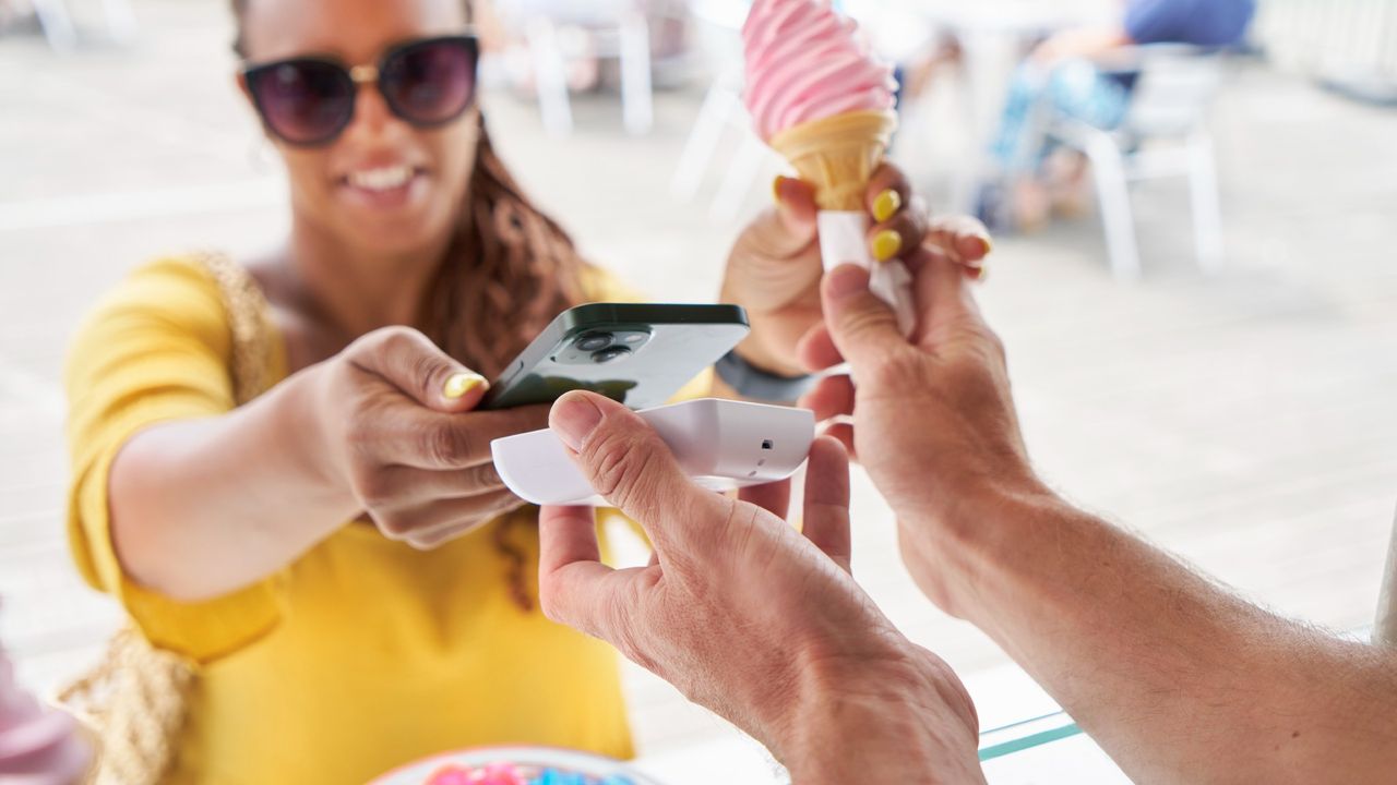 Woman buying an ice cream cone using tap and pay at outdoor cafe