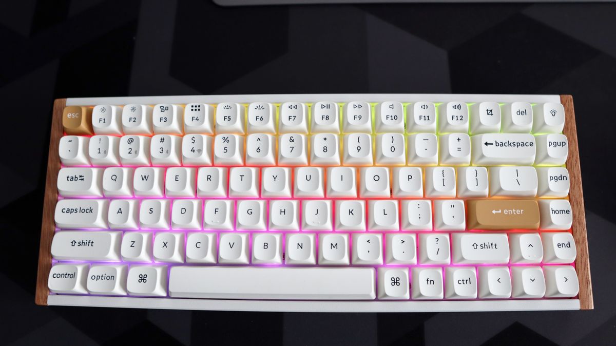 A Keychron K2 HE gaming keyboard with a wood finish and white keycaps with RGB enabled.