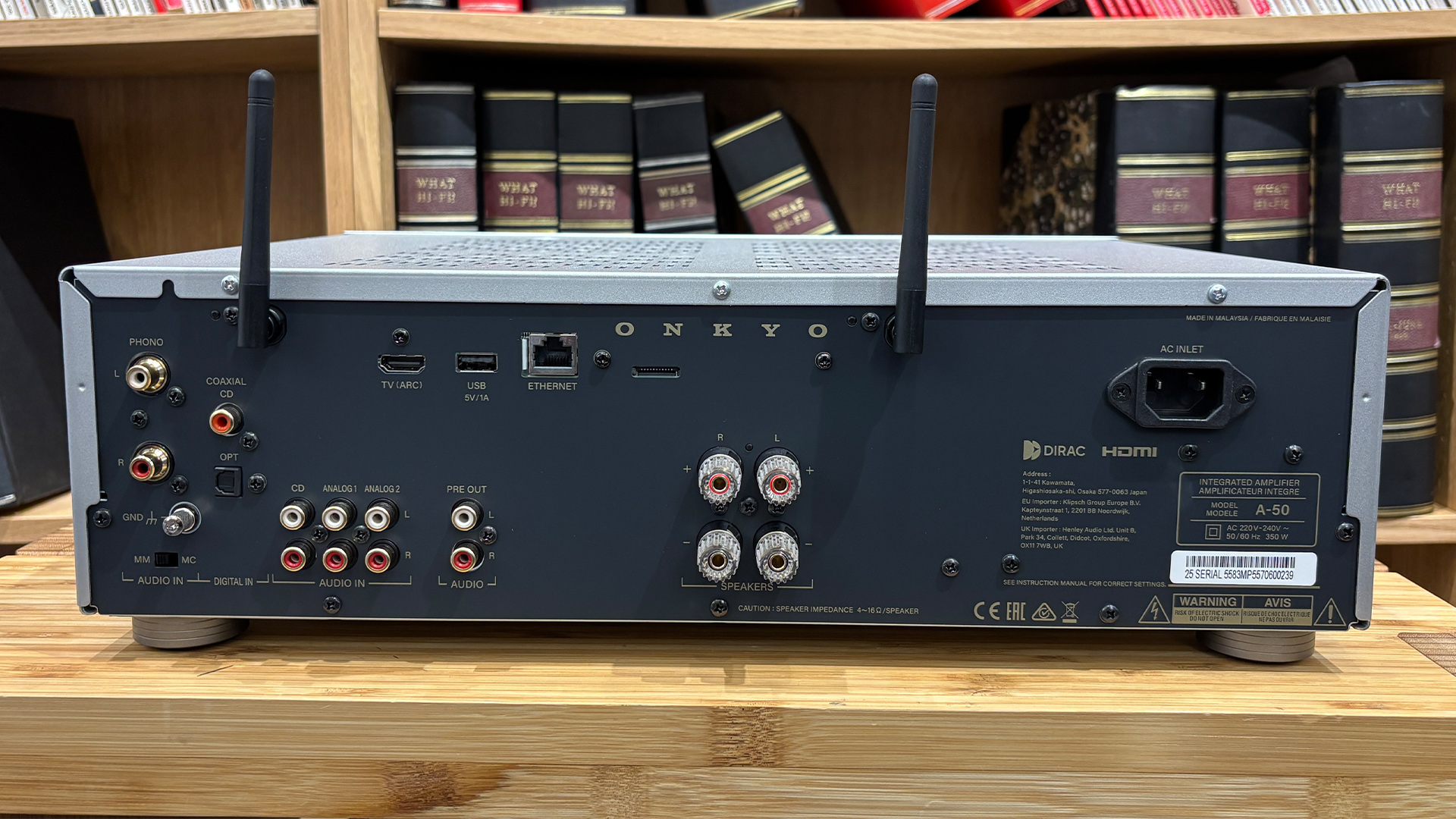 Onkyo Icon A-50 streaming amplifier on wooden hi-fi rack in front of bookcase, rear of unit