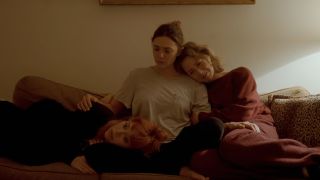 Carrie Coon, Natasha Lyonne, and Elizabeth Olsen snuggling on a couch at the end of His Three Daughters