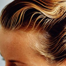 Woman with wet, combed hair, possibly while using a scalp treatment, close-up