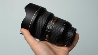 One of the best lenses for astrophotography in the hands of the author against a greeny blue background