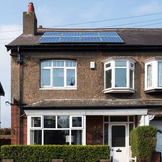 Exterior of a semi-detached pebble dashed house with solar panels on the roof