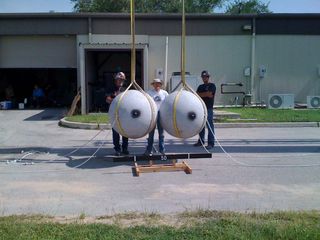 Scientists Dan Durda and two crane operators pose with two granite wrecking balls used to mimic asteroid collisions in an experiment at the Southwest Research Institute in Boulder, Colo.Institute