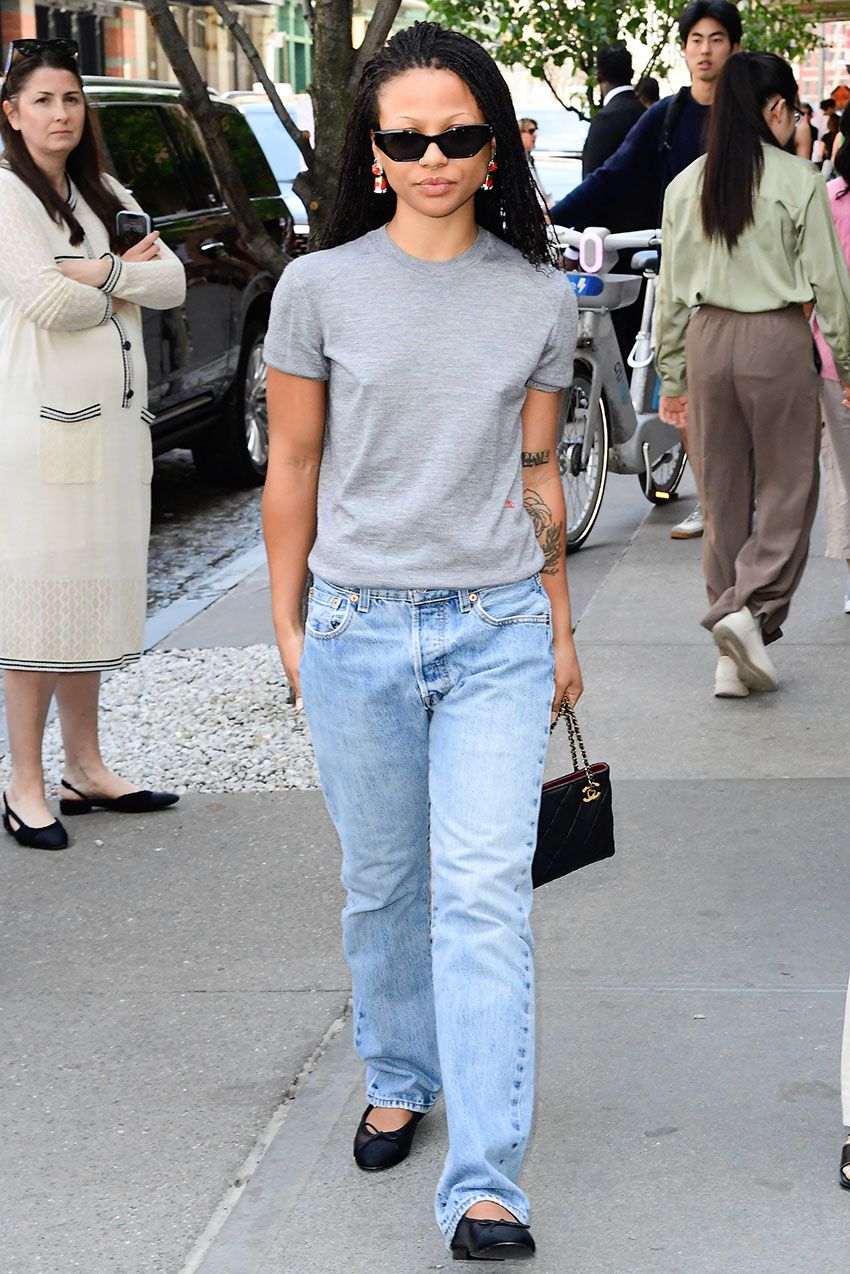 Myha'la wearing a gray T-shirt, blue jeans, black flats, black sunglasses, and a black Chanel handbag.