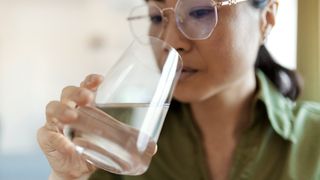 A woman drinks a glass of water