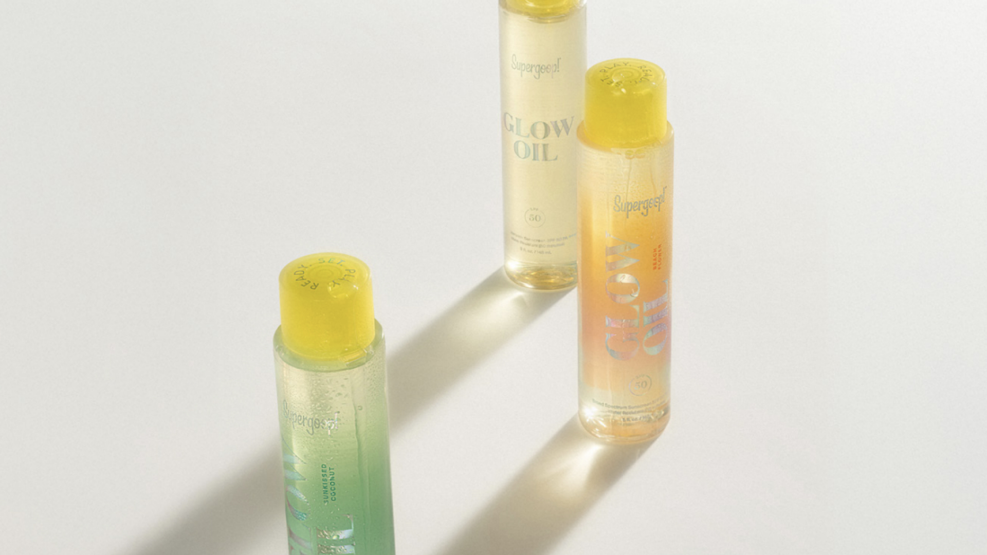 supergoop glow oil bottles sitting on beige background