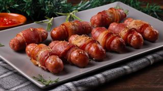 A tray of pigs in blankets displayed on a tea towel