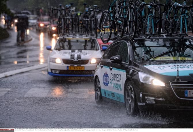 Team cars navigate the numerous puddles on the road