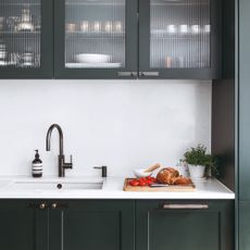 Dark kitchen cabinets with white countertop and sink