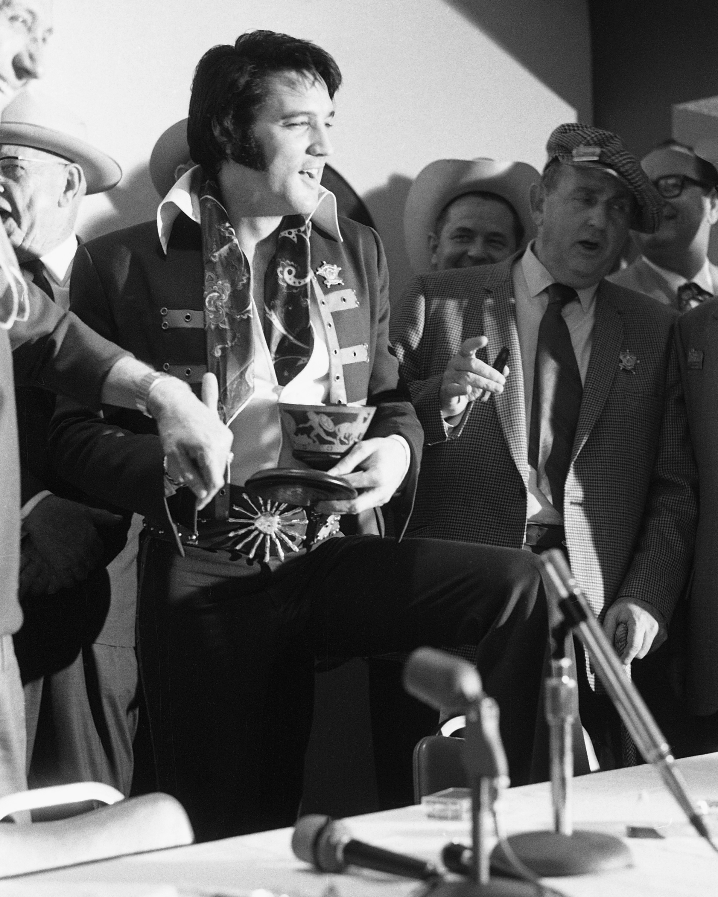 Black and white photograph of Elvis Presley standing in front of a microphone