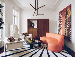 modern living room with curved orange couch and black and white rug