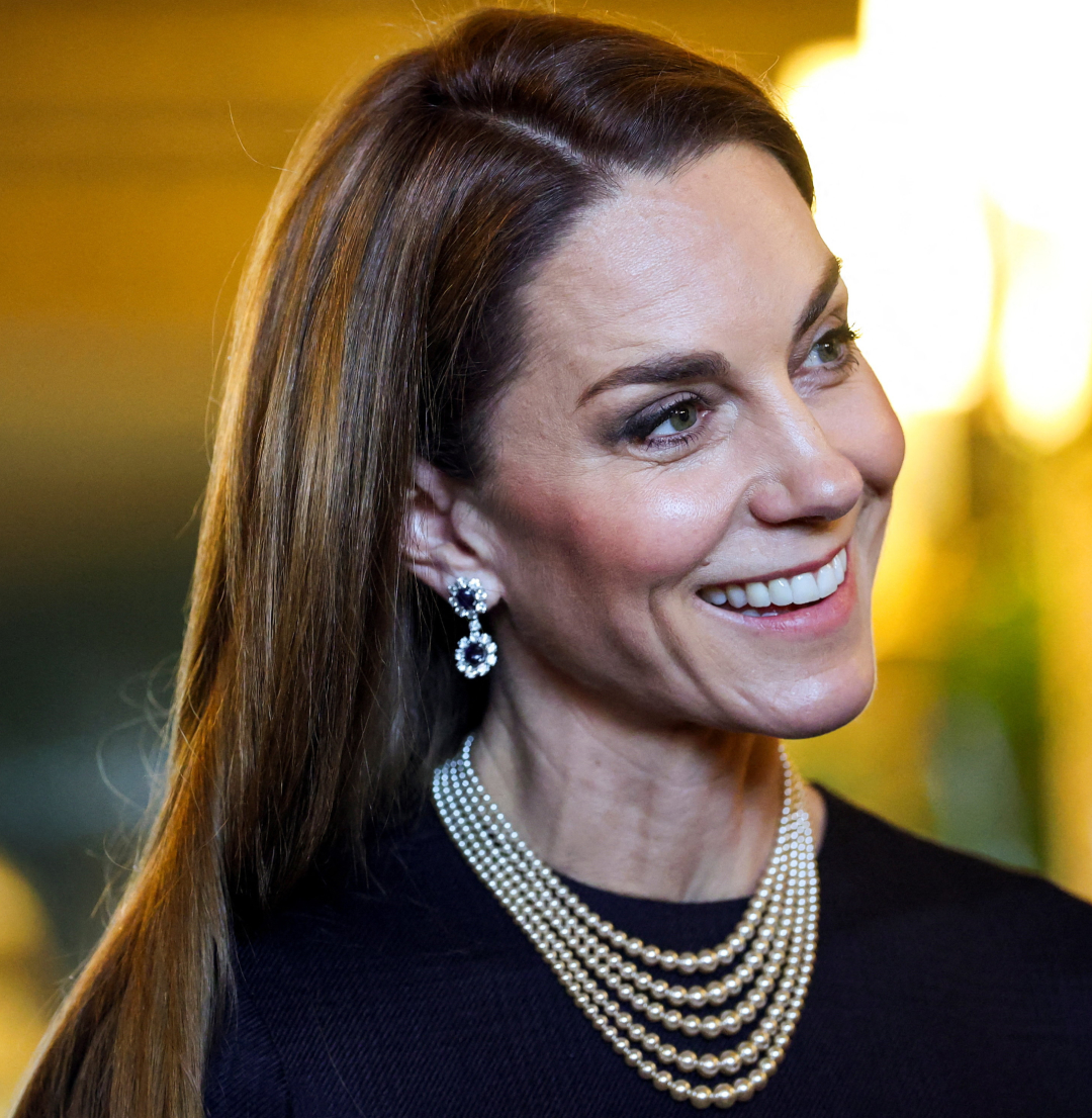 Princess Kate wearing a navy dress and pearls, smiling