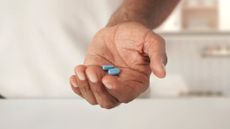 A photograph of a person holding two Journavx pain relief tablets.