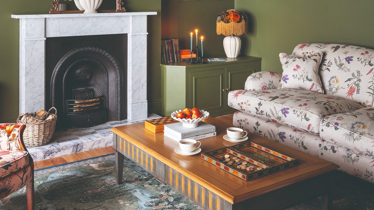 A green-painted living room with a marble fireplace and a floral cream sofa