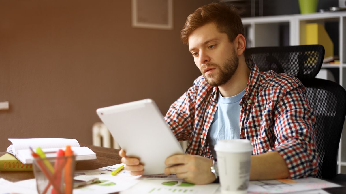 A person looking at an iPad while surrounded by office supplies