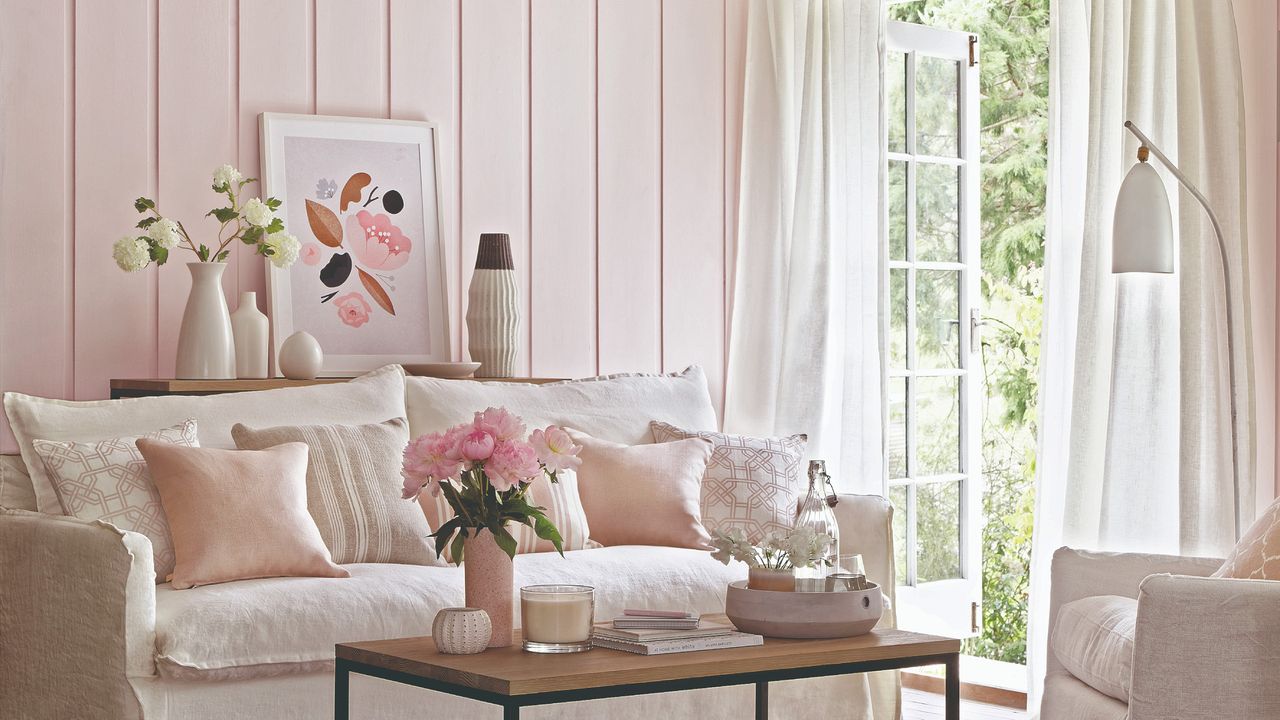 A living room with light pink-coloured tongue-and-groove panelling on the walls and a white sofa