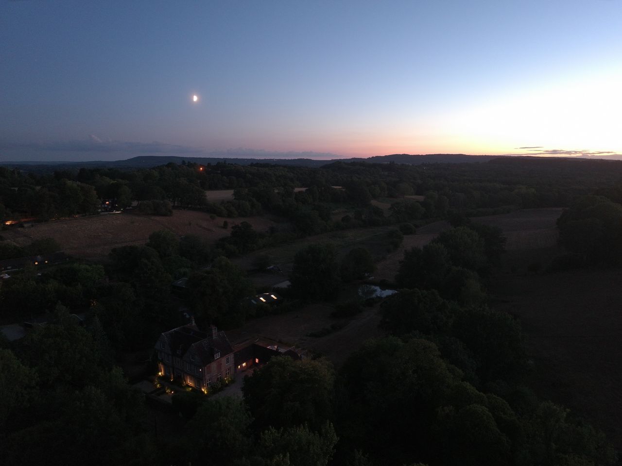 An aerial view of the UK countryside at last light - the moon is out, the sun is setting