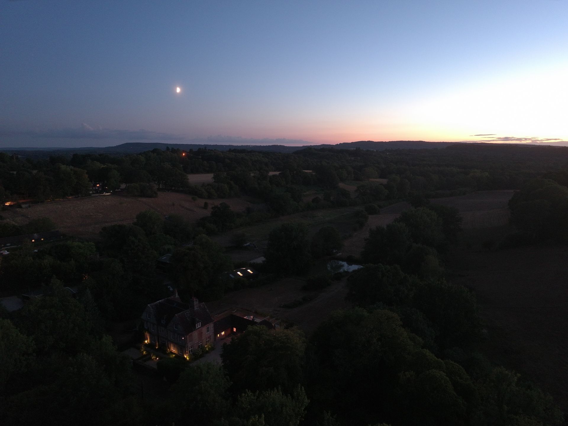 An aerial view of the UK countryside at last light - the moon is out, the sun is setting