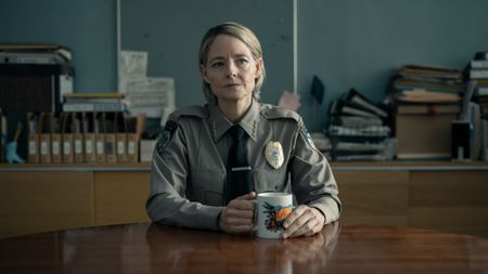 Chief Danvers sits at a table with a mug in True Detective: Night Country