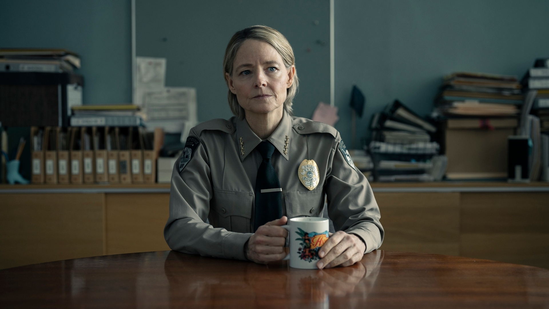 Chief Danvers sits at a table with a mug in True Detective: Night Country