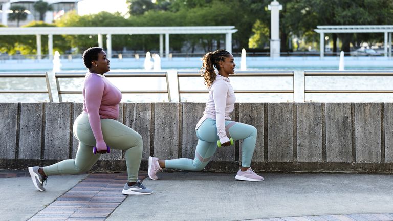 Two women performing dumbbell lunges