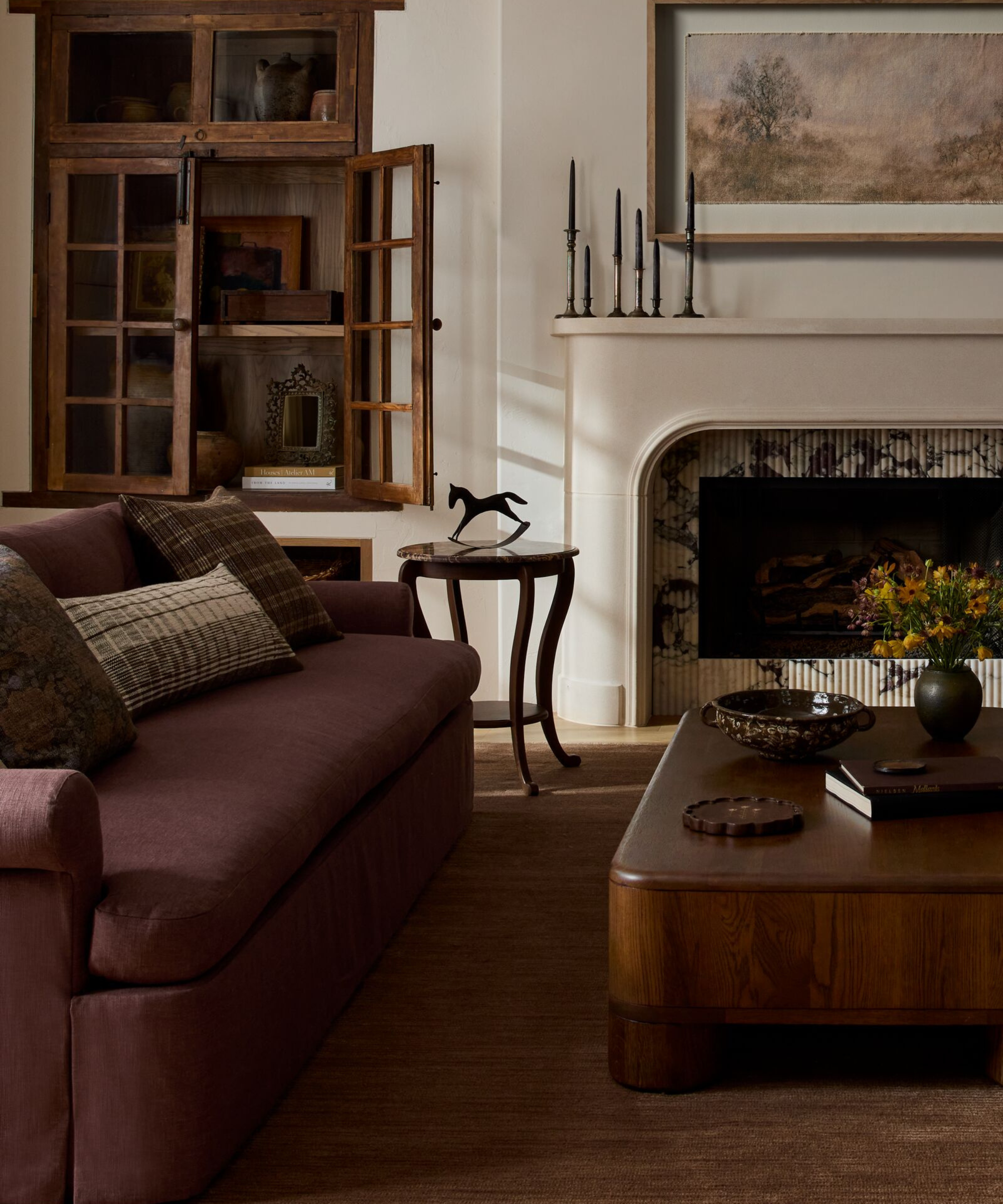a cozy living room with a plum-toned sofa and brown decor