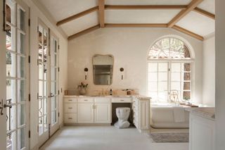 A large master bathroom with textural walls, a white vanity, a freestanding bathtub and carpeting