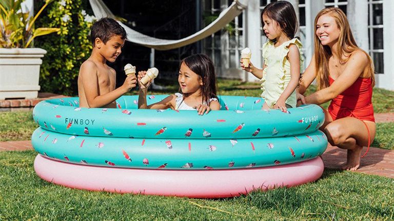 A family enjoying ice cream in cones sitting inside a colorful teal and pink inflatable paddling pool with ice cream motif