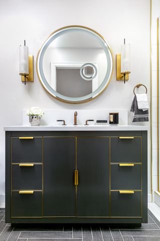 A bathroom with a black vanity and brass handles
