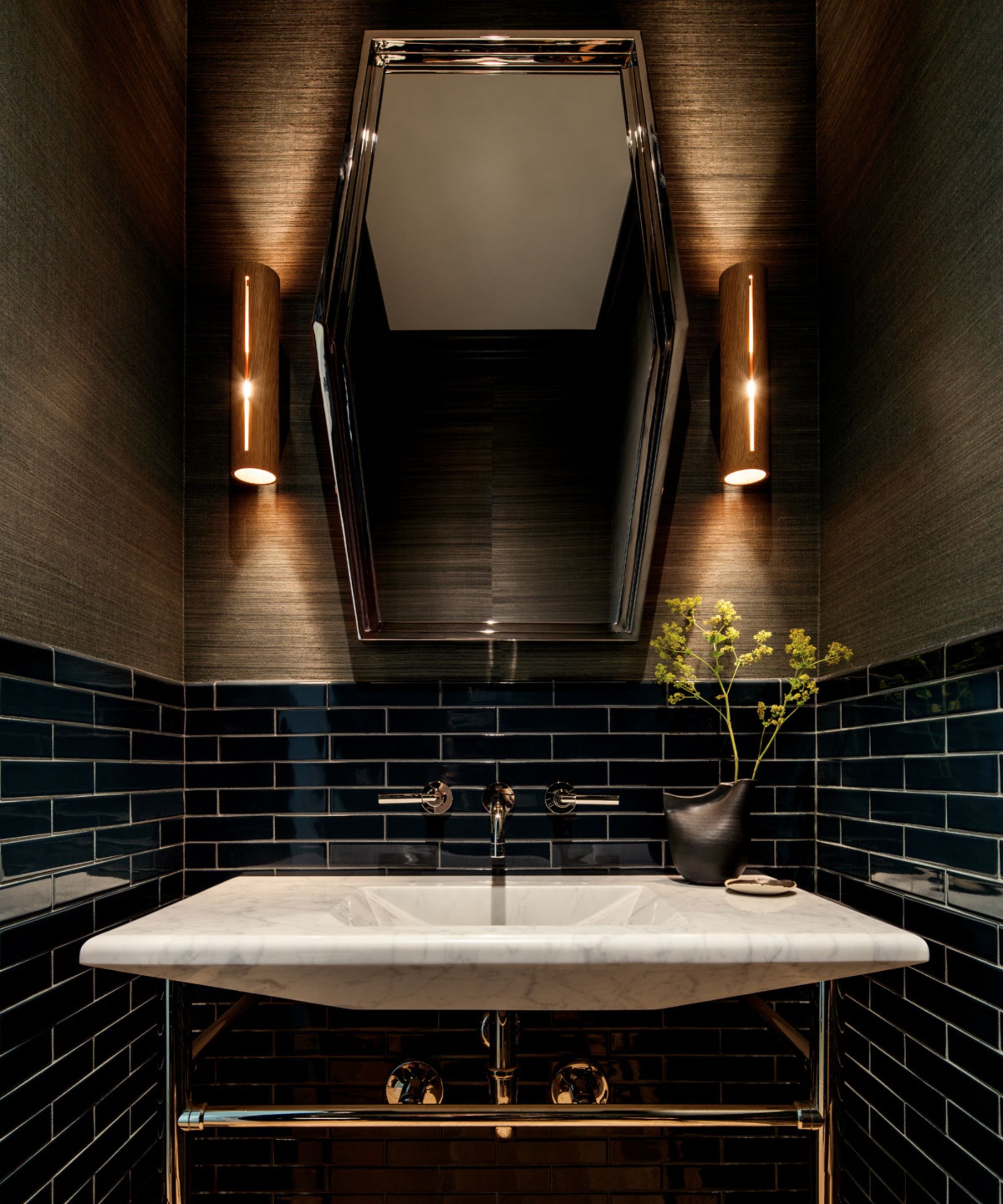 A moody bathroom with a marble sink and dark blue tiles