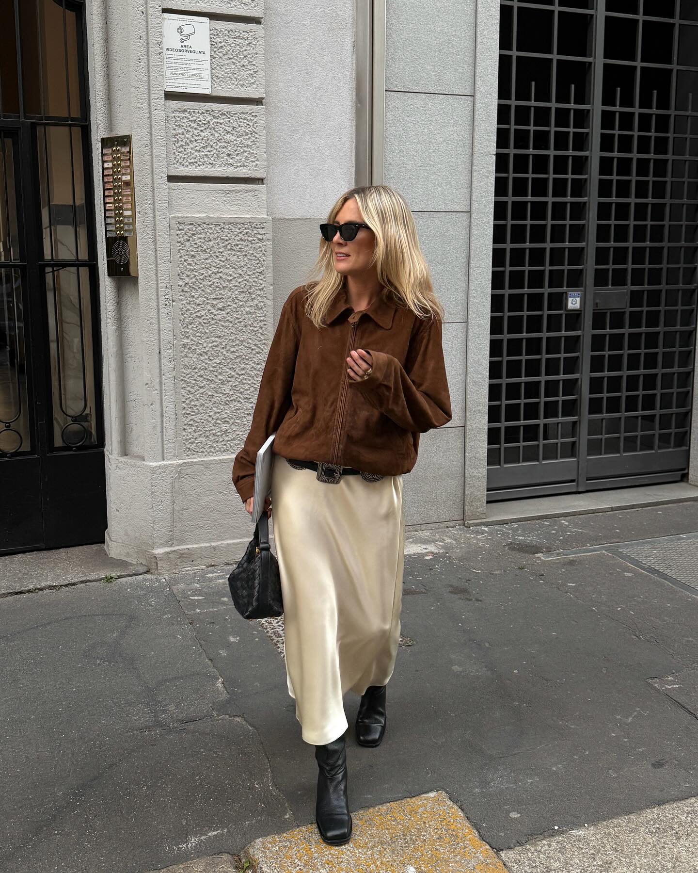 An image of @lucywilliams02 wearing a buttery silk skirt with a suede jacket, black leather boots and a woven leather bag.