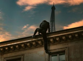 A man climbing onto the rood of a building with the Eiffel Tower in the background