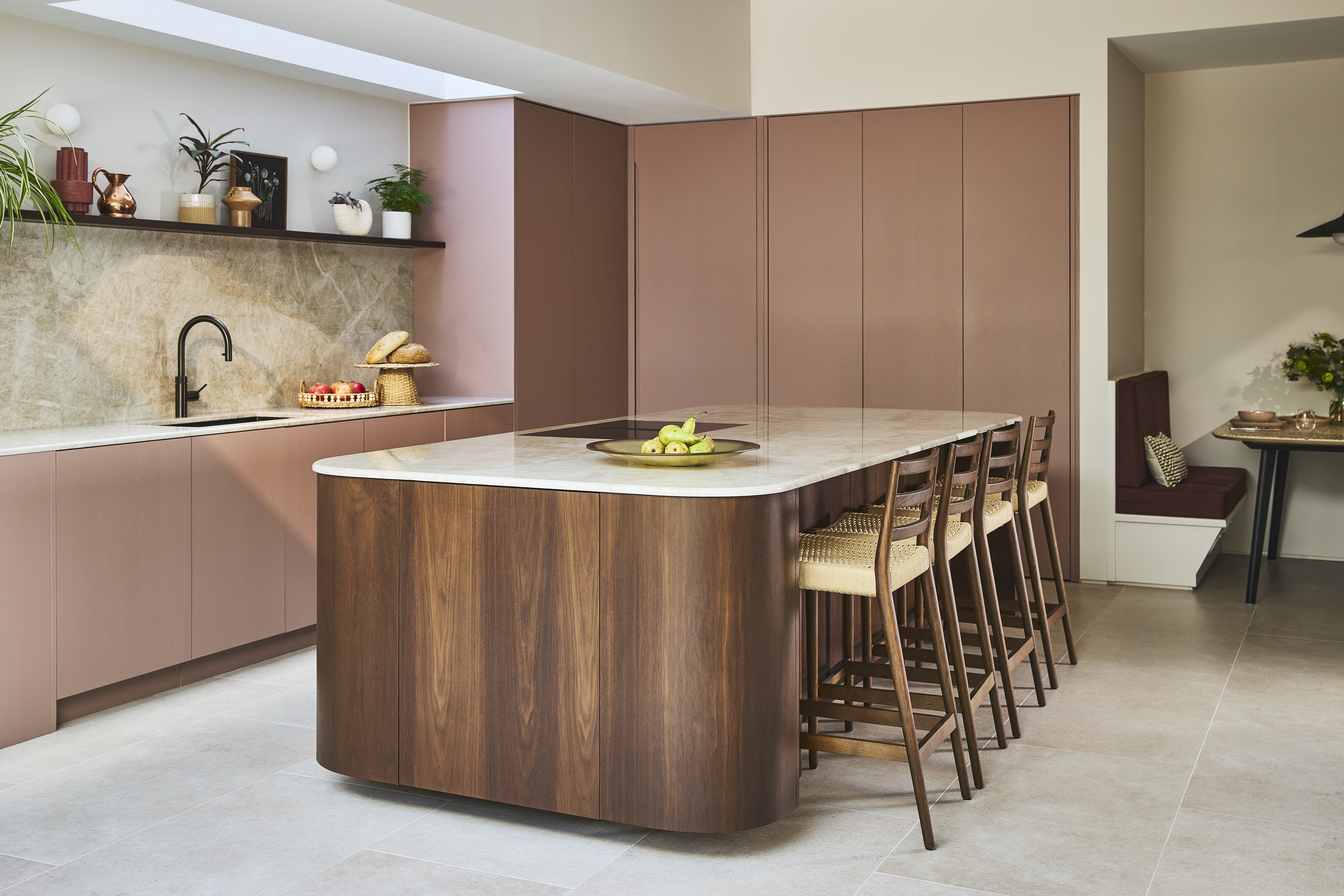 modern kitchen with dusty pink handless cabinets and a wooden curved kitchen island