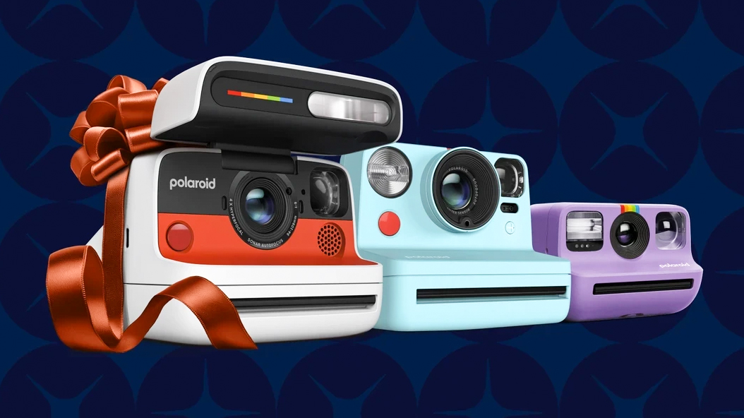 A row of Polaroid cameras, wrapped in a bow, against a blue background