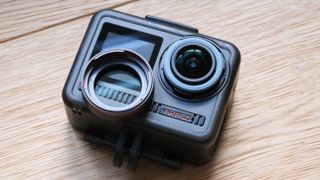 Akaso Brave 8 action camera on a wooden surface with its lens protection cover removed