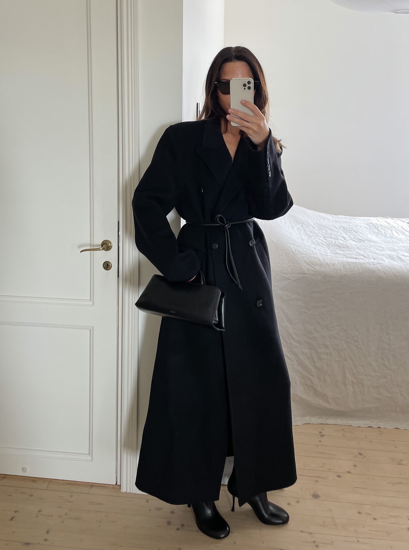 @johannapiispa wears &quot;toy&quot; boot, one of the biggest winter 2025 boot trends, with a black trench coat and east-west bag.