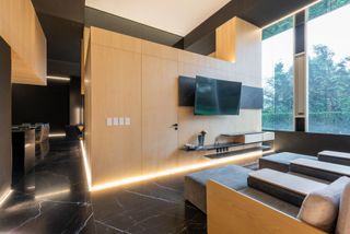 Cinema room with dark marble floor and light wood at Llano Apartment, Mexico City, by Archetonic