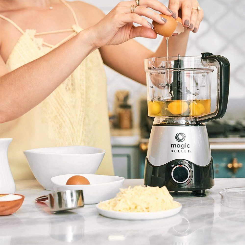 Woman in a cream top breaking eggs into a Magic Bullet food processor