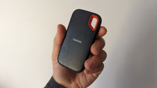 a hand holding a small black rectangle with the word "sandisk" on it