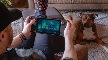 Person playing with the Steam Deck with dog in photo