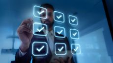 A businessman ticking holographic blue check marks on a screen, to represent an IT audit.