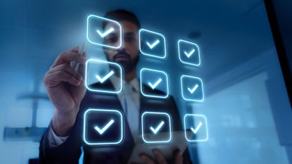 A businessman ticking holographic blue check marks on a screen, to represent an IT audit.