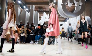 Models wear light pink mini dress, and baby pink coat with white boots