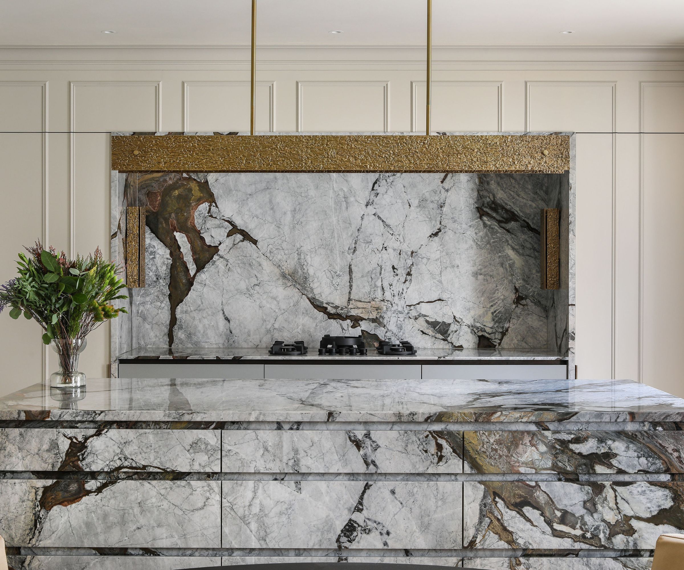 A modern kitchen with taupe cabinets and marble countertops